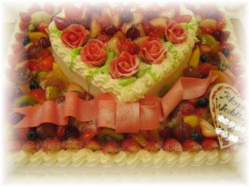 12月のご注文です。大きな４０名様用サイズのケーキの上に、８号サイズのハートのケーキを重ねました。チョコレートで作ったバラの花と、大きなリボンとで、豪華なウエディングケーキが出来上がりました。